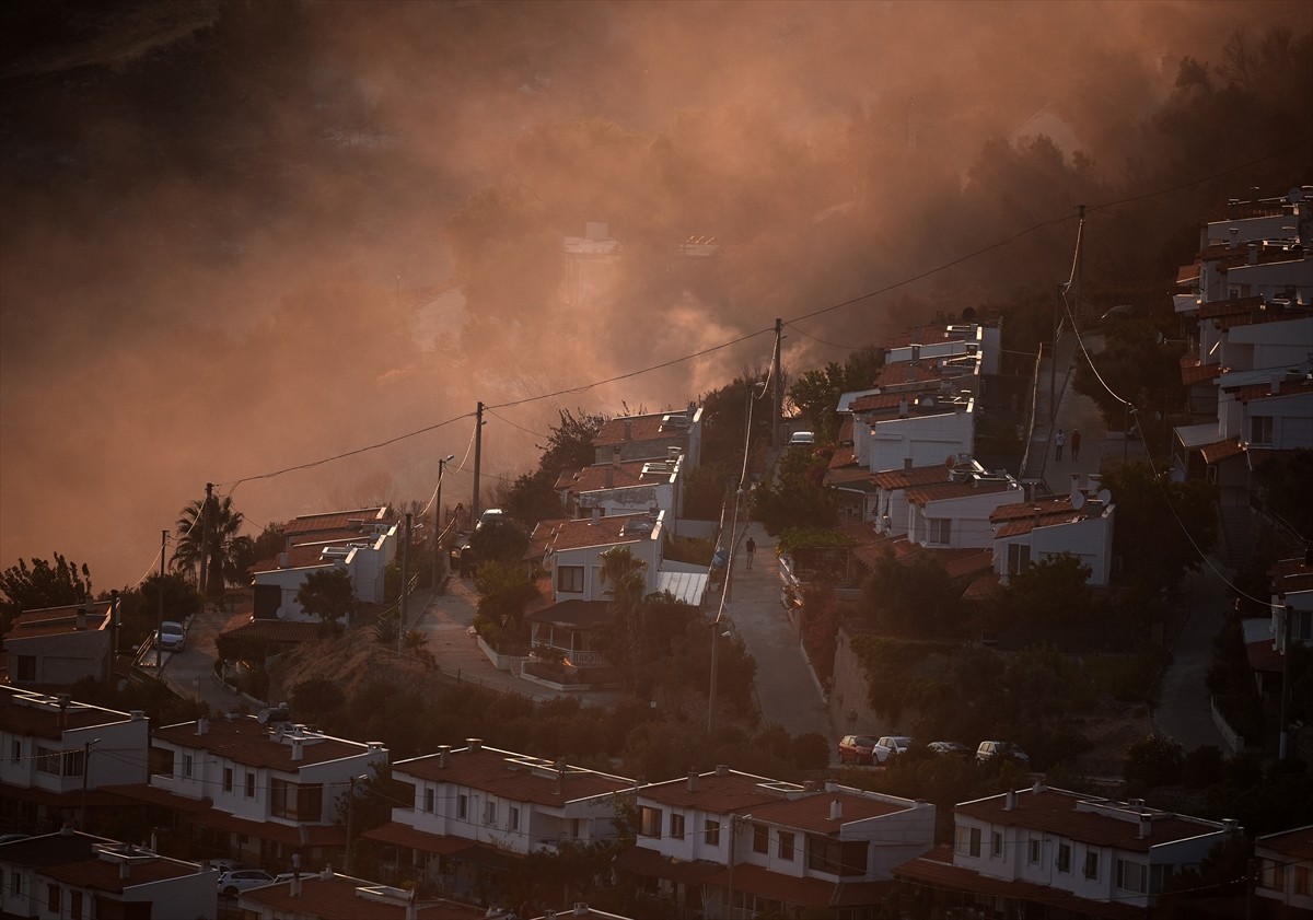 İzmir'in Dikili ilçesinde ormanlık alanda başlayan ve yerleşim yerlerine yaklaşan yangına havadan...