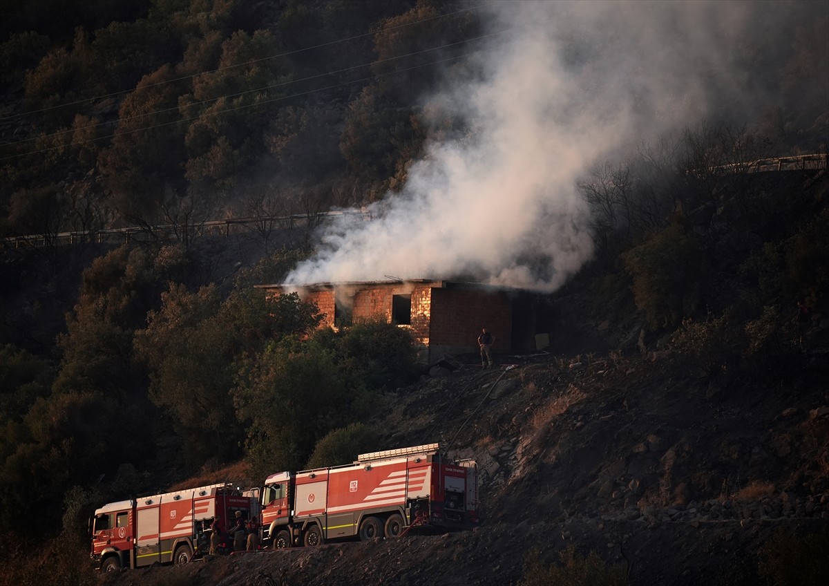 İzmir'in Dikili ilçesinde ormanlık alanda başlayan ve yerleşim yerlerine yaklaşan yangına havadan...