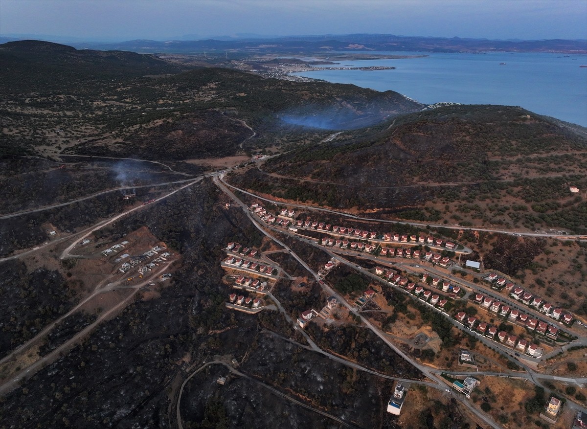 İzmir'in Dikili ilçesinde ormanlık alanda başlayan ve yerleşim yerlerine yaklaşan yangına havadan...