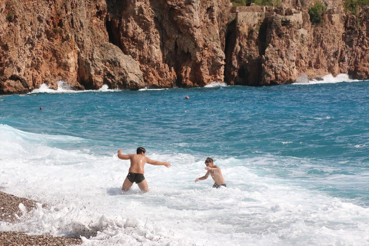 Antalya'da havanın bulutlu ve suyun dalgalı olmasına rağmen bazı yabancı turistler denizde...